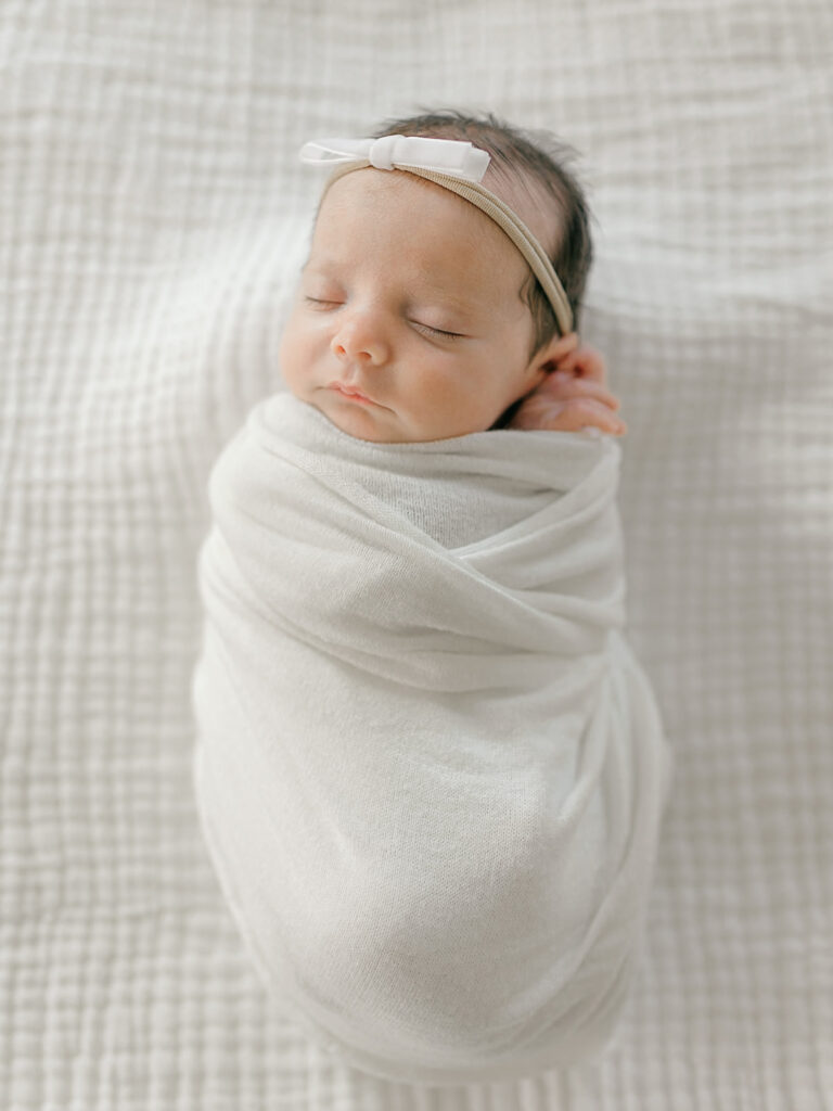 newborn baby girl swaddled on bed