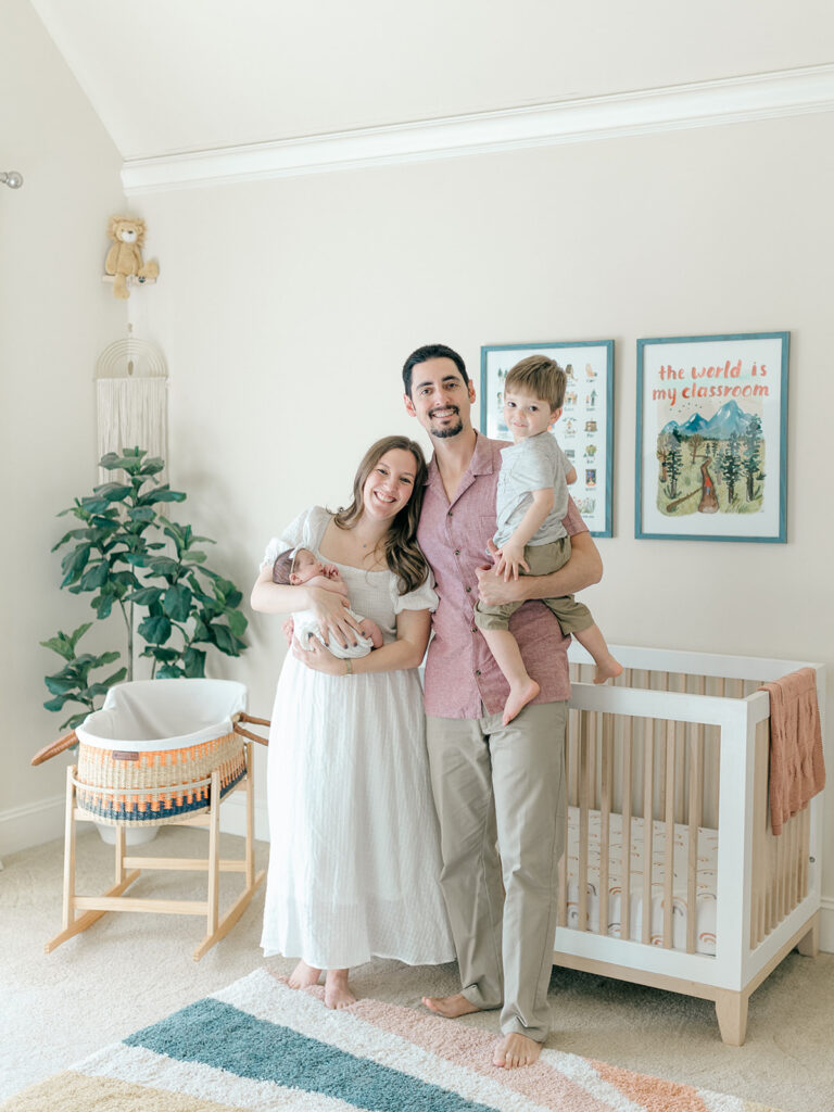 Family standing in front of crib with newborn baby girl