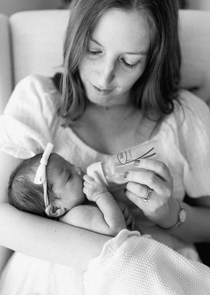 mother in black and white image feeding newborn baby girl 